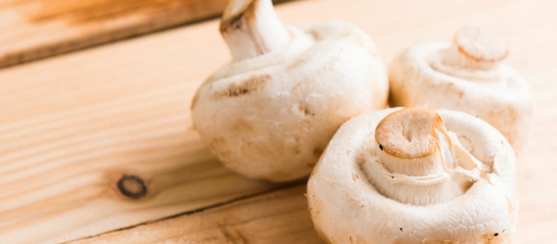 three-white-mushrooms-on-beige-wooden-table-793267